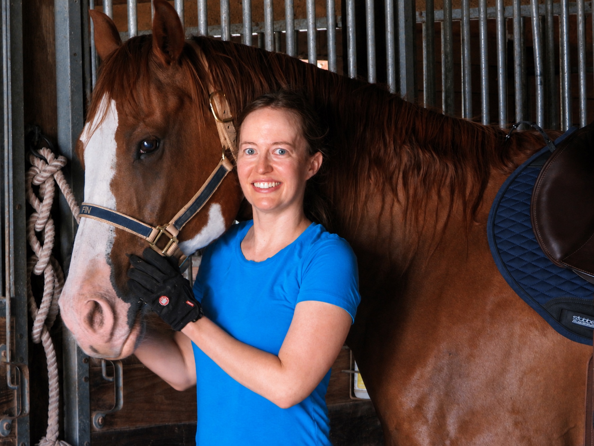 Smiling rider with a horse in the barn