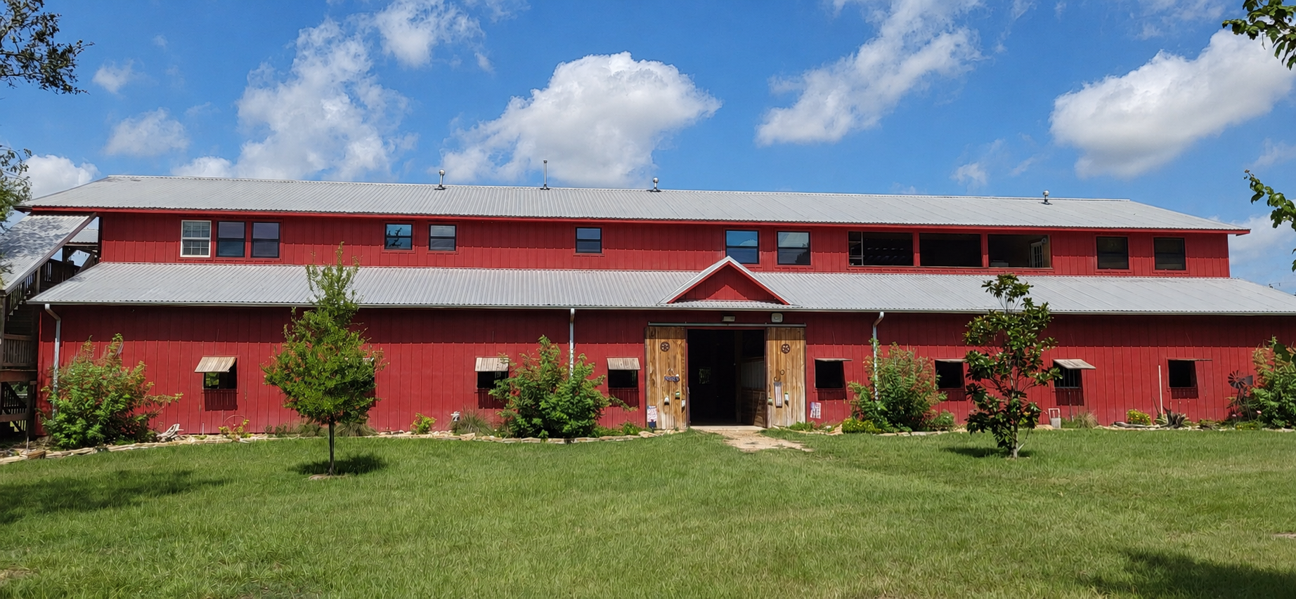 The long red barn against a green lawn
